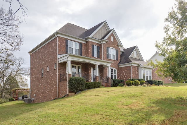 view of front facade featuring a front yard, central air condition unit, and covered porch