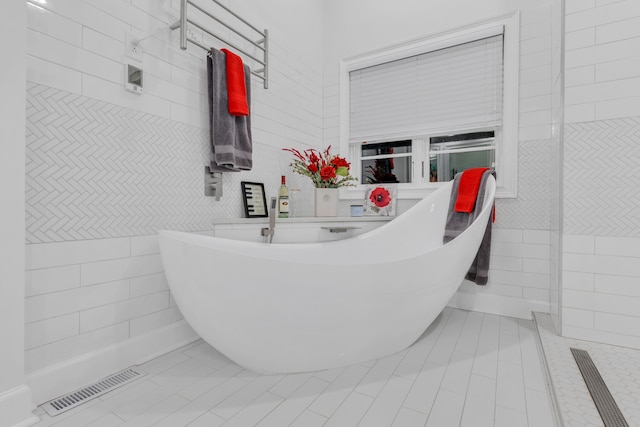 bathroom with tile patterned floors, a bathtub, and tile walls