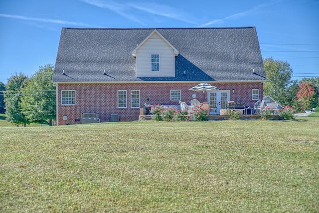 rear view of house with central AC and a lawn