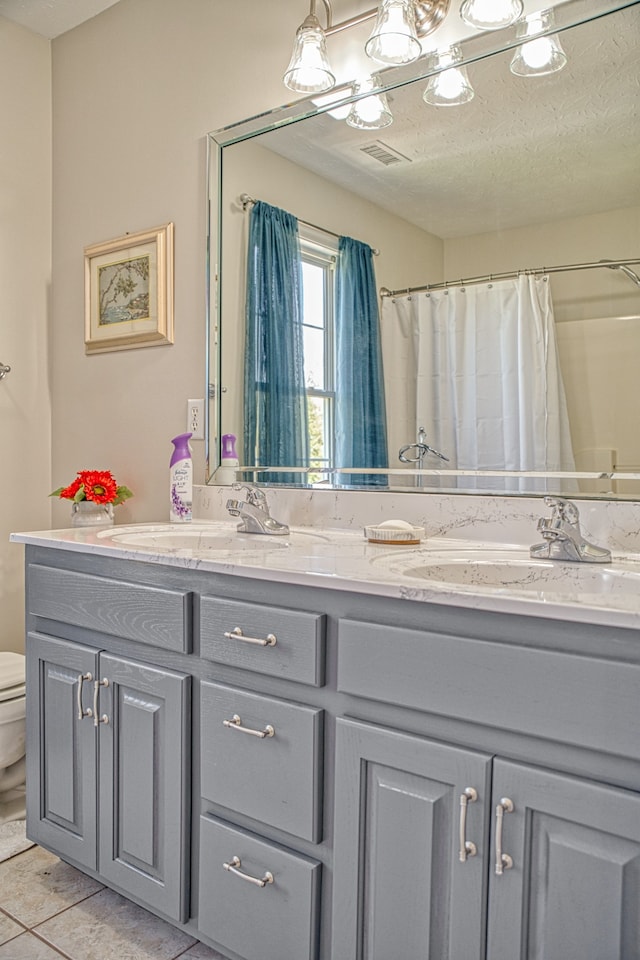 bathroom with tile patterned flooring, vanity, toilet, and a textured ceiling