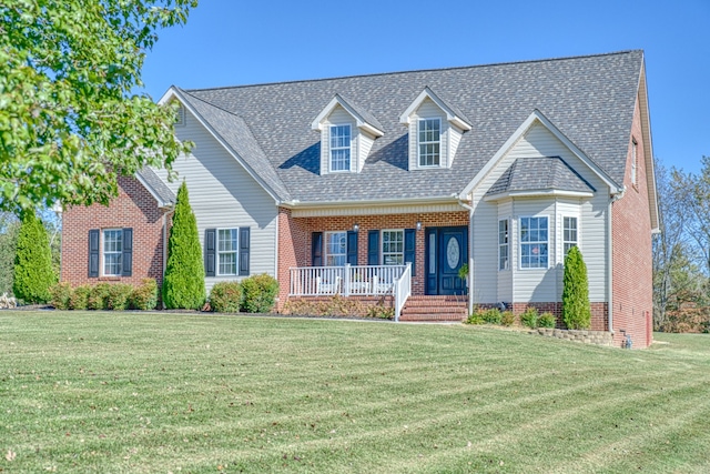 cape cod home featuring covered porch and a front yard