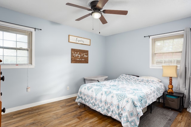 bedroom featuring multiple windows, ceiling fan, and dark hardwood / wood-style floors