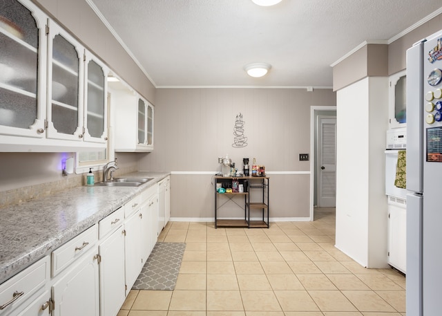 kitchen with white cabinetry, sink, light tile patterned floors, and ornamental molding