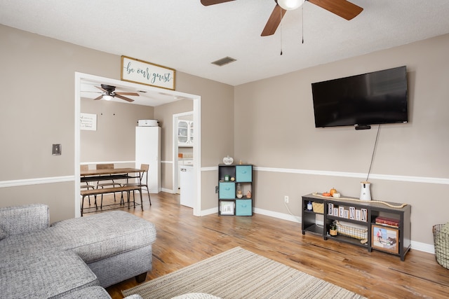 living room featuring ceiling fan, wood-type flooring, and a textured ceiling