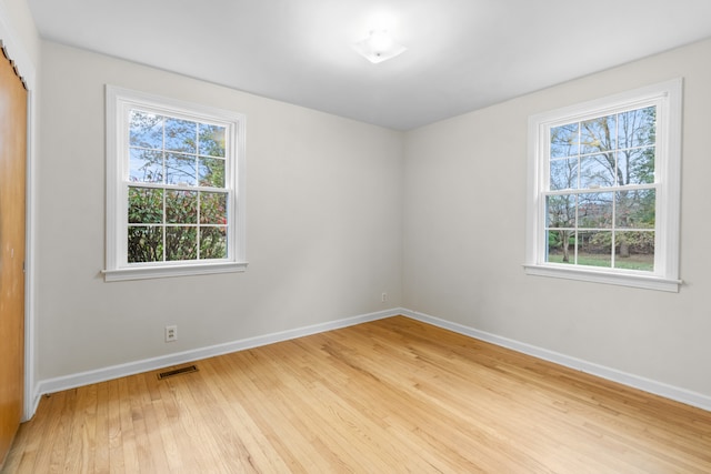 empty room with hardwood / wood-style flooring and a healthy amount of sunlight