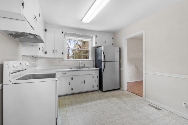 kitchen featuring white range oven, stainless steel fridge, sink, and white cabinetry