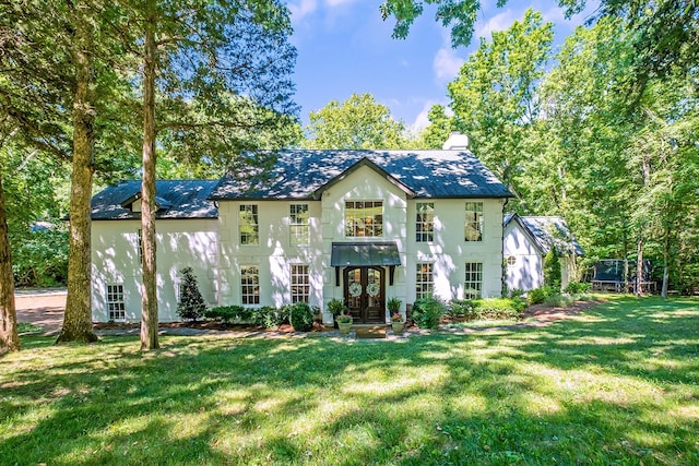 view of front of home with a front yard, french doors, and a trampoline