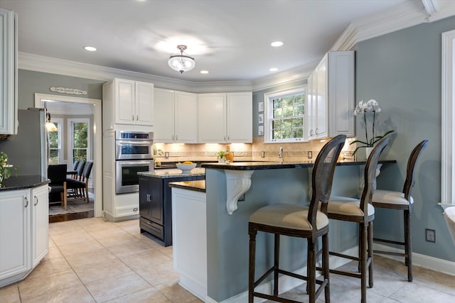 kitchen with double oven, a wealth of natural light, white cabinetry, and ornamental molding