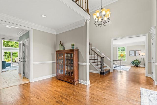 foyer entrance featuring hardwood / wood-style floors, ornamental molding, and a chandelier