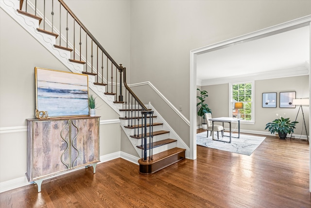 stairway with ornamental molding and hardwood / wood-style flooring