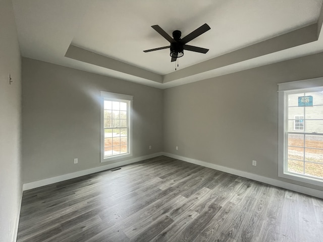 spare room with a tray ceiling, ceiling fan, and hardwood / wood-style flooring