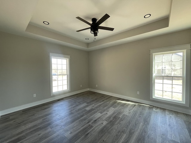 unfurnished room with dark wood-style floors, a raised ceiling, and baseboards