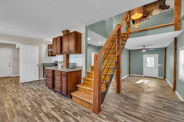 kitchen with stainless steel electric range, hardwood / wood-style flooring, ceiling fan, backsplash, and light stone countertops