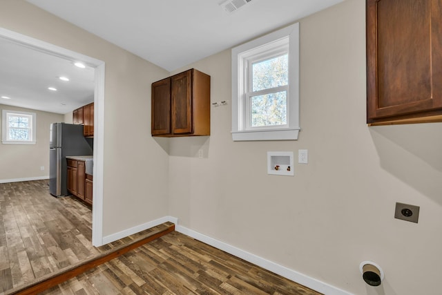 washroom featuring cabinets, hookup for a washing machine, dark hardwood / wood-style floors, and hookup for an electric dryer