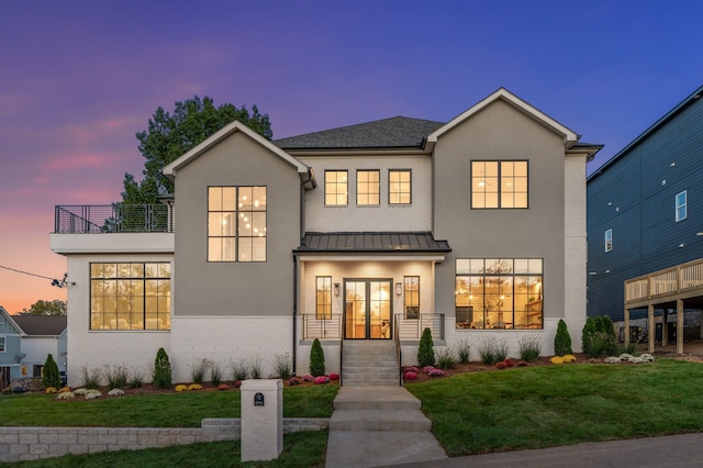 view of front of home featuring a lawn, a balcony, and french doors