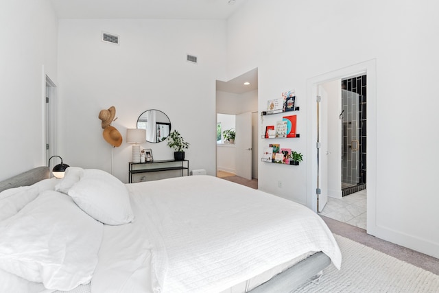 bedroom featuring ensuite bathroom, high vaulted ceiling, and light colored carpet