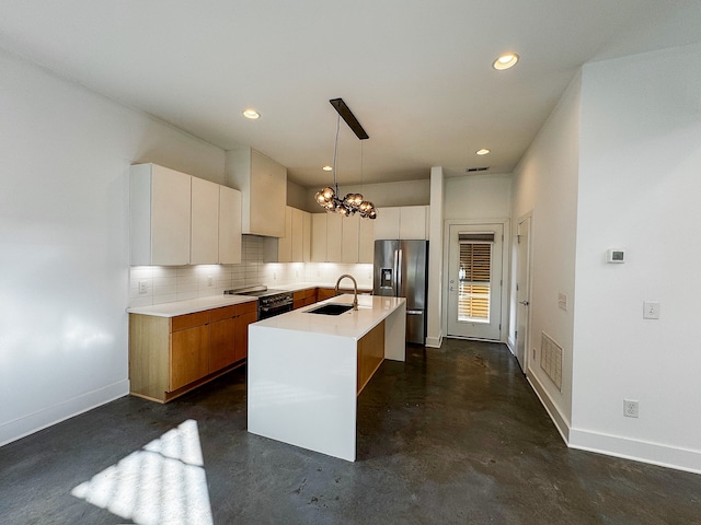 kitchen featuring white cabinetry, sink, stainless steel appliances, pendant lighting, and a kitchen island with sink