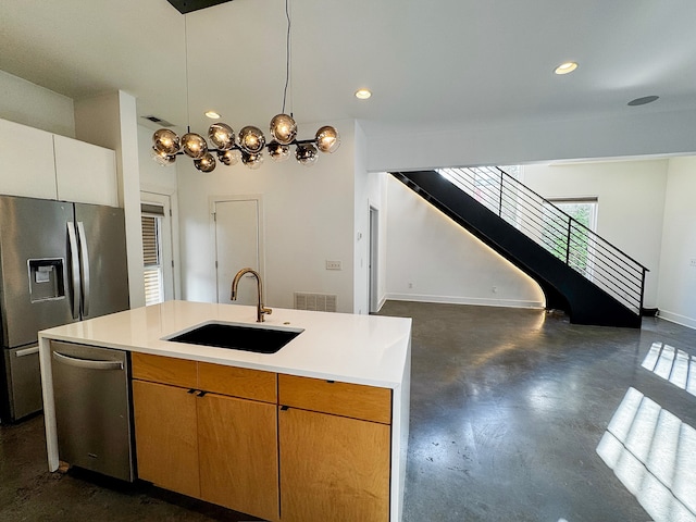 kitchen featuring pendant lighting, sink, appliances with stainless steel finishes, and an island with sink