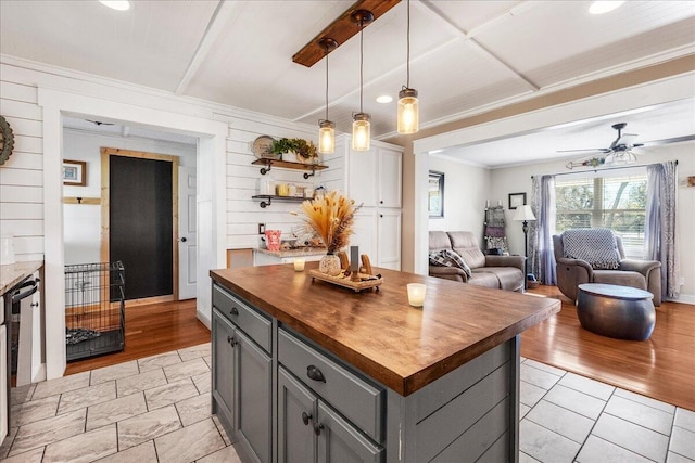 kitchen featuring pendant lighting, wood counters, gray cabinets, light wood-type flooring, and a kitchen island