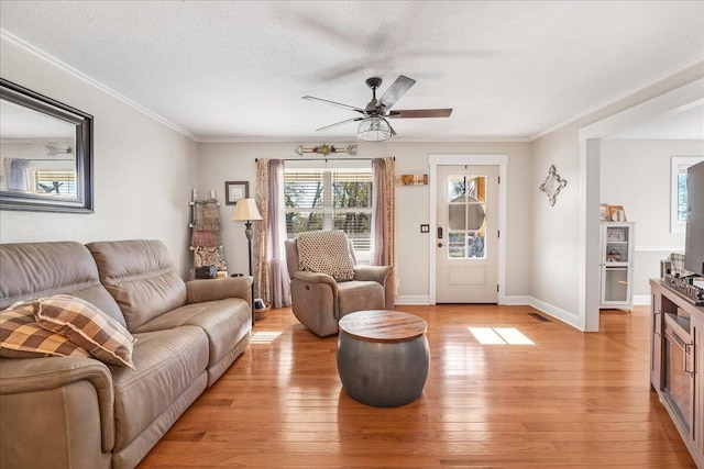 living room featuring ceiling fan, light hardwood / wood-style flooring, crown molding, and a textured ceiling