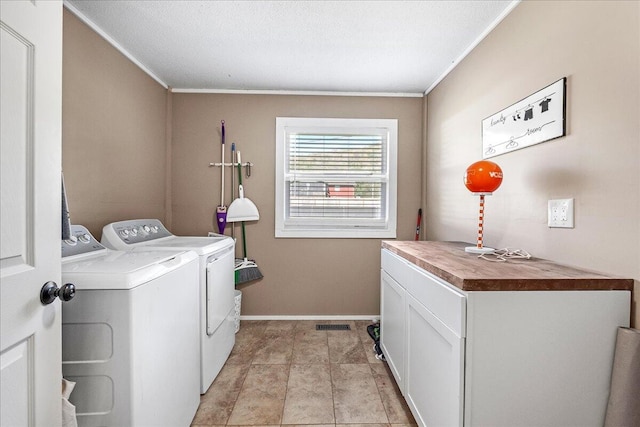 clothes washing area with washer and clothes dryer, cabinets, a textured ceiling, and ornamental molding