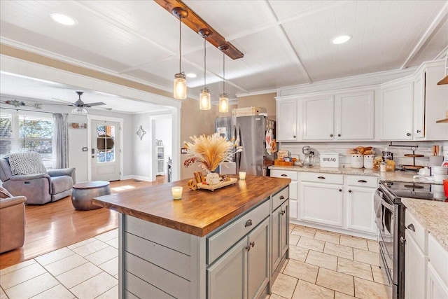 kitchen with a center island, white cabinetry, stainless steel appliances, and wooden counters