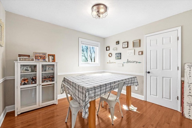 dining space with wood-type flooring and a textured ceiling