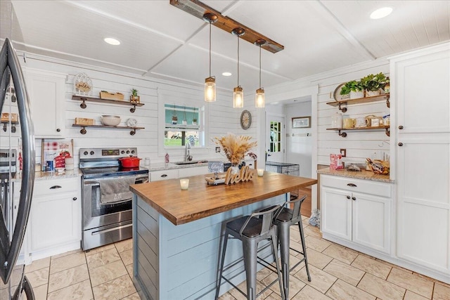 kitchen with appliances with stainless steel finishes, a center island, decorative light fixtures, and white cabinetry