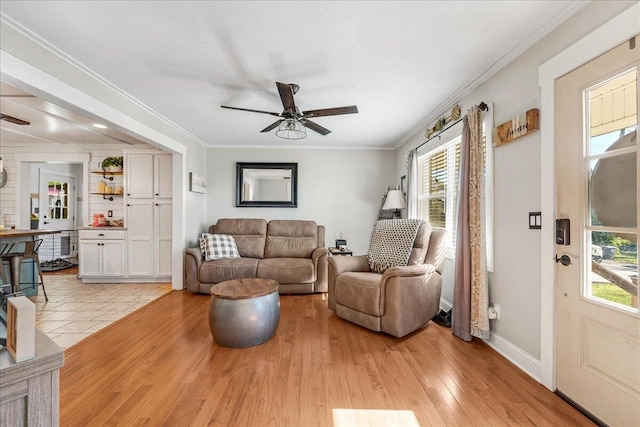 living room featuring a wealth of natural light, crown molding, ceiling fan, and light hardwood / wood-style floors