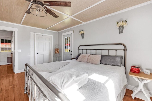 bedroom featuring hardwood / wood-style floors, crown molding, ceiling fan, wood ceiling, and a closet