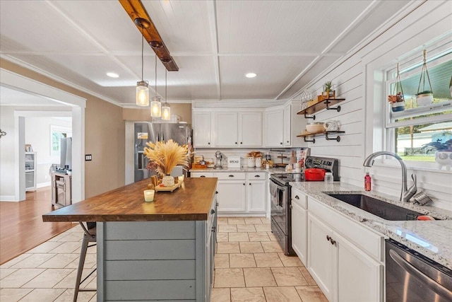 kitchen featuring white cabinetry, stainless steel appliances, butcher block countertops, a breakfast bar, and a kitchen island