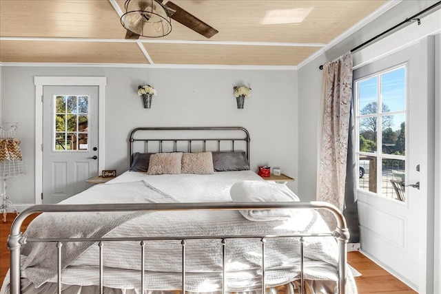 bedroom featuring hardwood / wood-style floors, ceiling fan, crown molding, and multiple windows