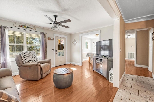 living room featuring a textured ceiling, ceiling fan, light hardwood / wood-style floors, and crown molding