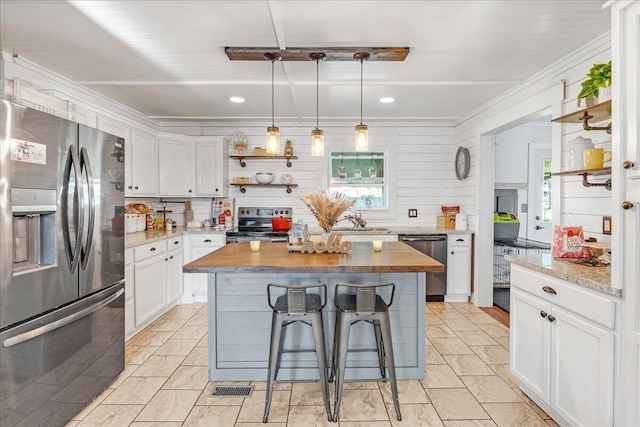 kitchen featuring a kitchen bar, appliances with stainless steel finishes, pendant lighting, a center island, and white cabinetry