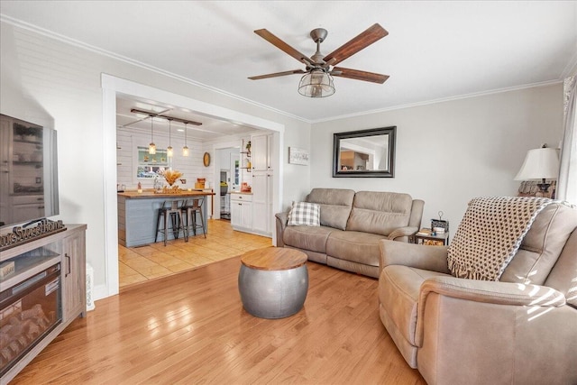 living room with ceiling fan, light hardwood / wood-style floors, and crown molding