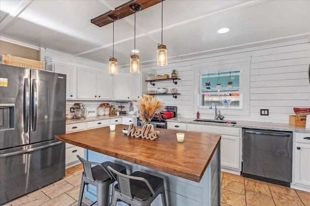 kitchen with wooden counters, white cabinets, sink, appliances with stainless steel finishes, and a kitchen island