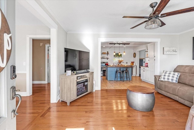 living room featuring ceiling fan, light hardwood / wood-style floors, and ornamental molding