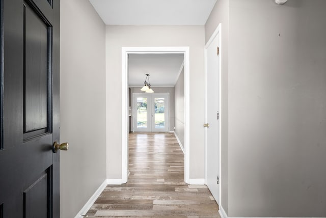 hall featuring wood-type flooring, crown molding, and french doors