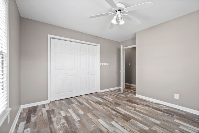 unfurnished bedroom featuring ceiling fan, a closet, and light wood-type flooring