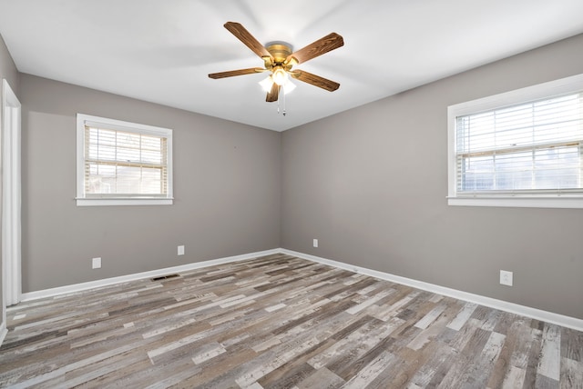 empty room with ceiling fan, plenty of natural light, and light hardwood / wood-style floors