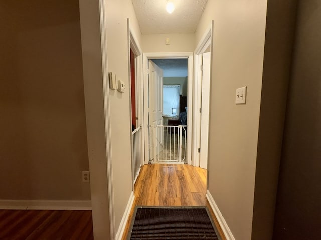 hallway with wood-type flooring and a textured ceiling