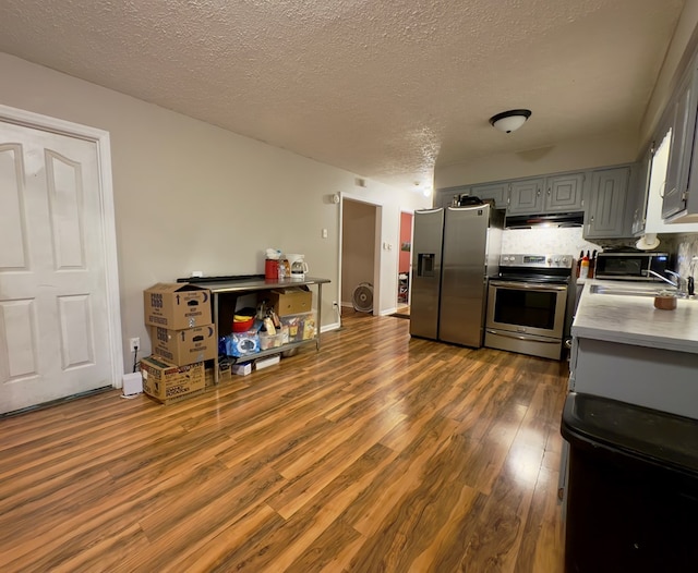 kitchen with appliances with stainless steel finishes, dark hardwood / wood-style flooring, tasteful backsplash, gray cabinetry, and sink