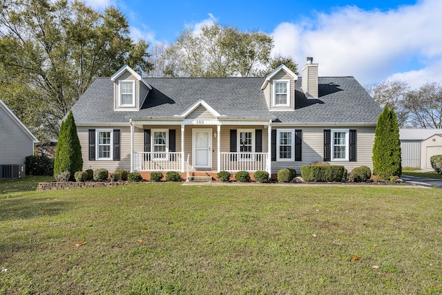 cape cod home with cooling unit, covered porch, an outdoor structure, and a front yard