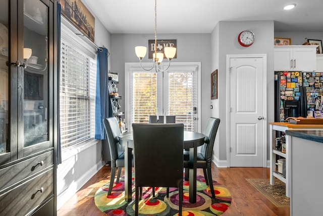 dining space with dark wood-type flooring and a notable chandelier