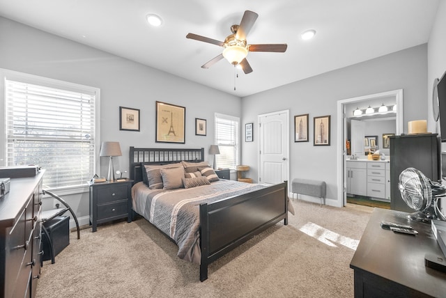 bedroom featuring ceiling fan, light colored carpet, connected bathroom, and multiple windows