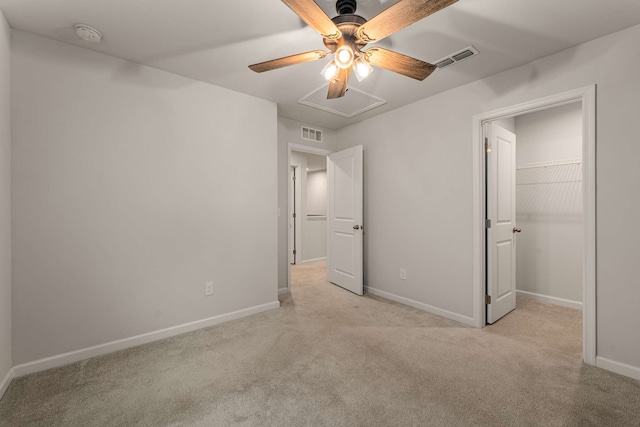 unfurnished bedroom featuring ceiling fan, light colored carpet, a walk in closet, and a closet