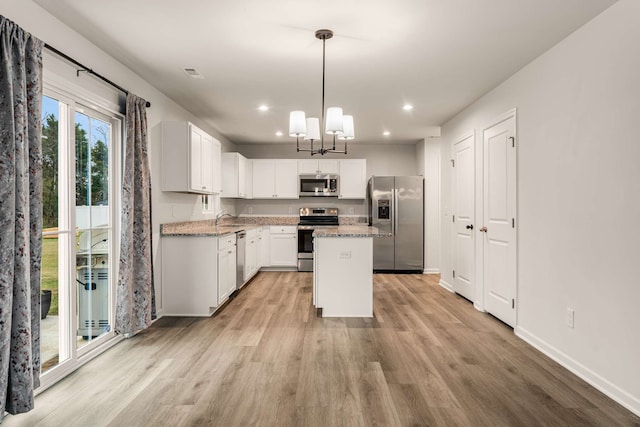 kitchen with a center island, stainless steel appliances, light hardwood / wood-style flooring, pendant lighting, and white cabinets