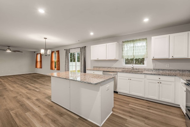 kitchen with white cabinets, light wood-type flooring, a kitchen island, and sink