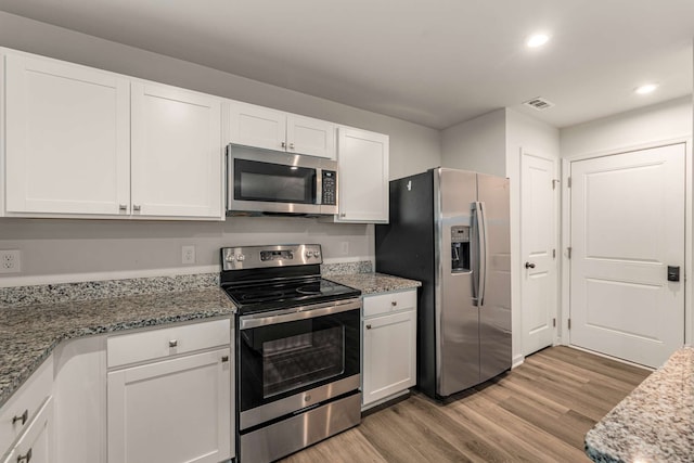 kitchen featuring white cabinets, light stone counters, light wood-type flooring, and appliances with stainless steel finishes