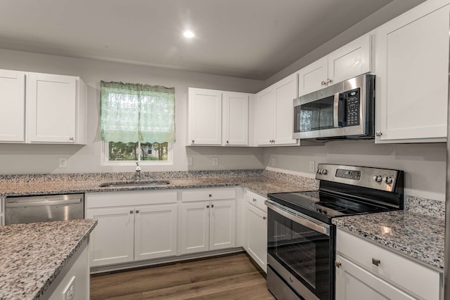 kitchen with stainless steel appliances, white cabinetry, dark wood-type flooring, and sink